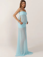 Woman wearing a light blue dress with a sheer overlay on a plain background